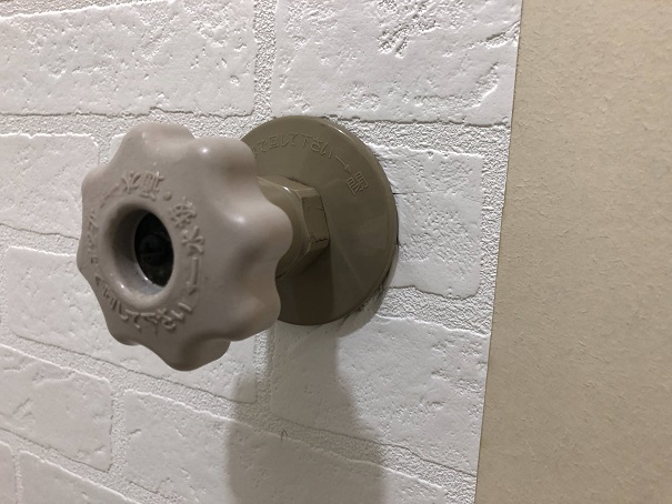 壁紙を貼り終わり、水抜き栓のパーツを壁に戻したところ