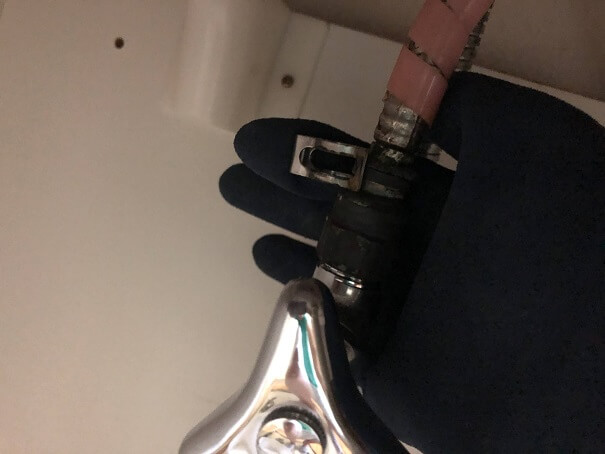 洗面台下の止水栓との接続部分についていた金具を外すところ