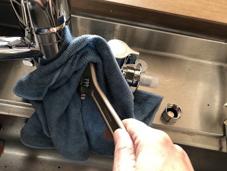 分岐水栓金具に傷がつかないようにタオルを巻いてスパナで固定するところ
